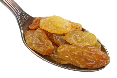 In the old golden spoon there is a small heap  of food -dry amber  rasins fruits berries. Isolated on white studio macroの写真素材
