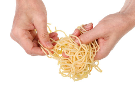Old poor man eat with hands  long boiled spaghetti pasta with fatty butter . Isolated on white studio closeupの写真素材
