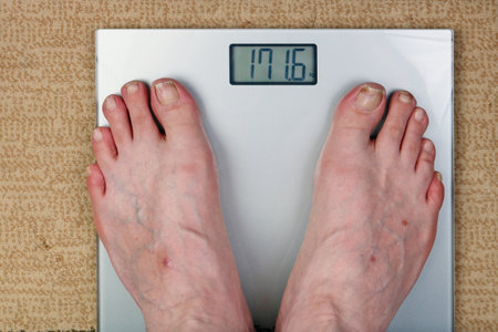 An old man controls his weight on electric floor scales. Obesity aggravates all diseases concept