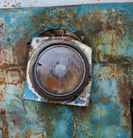 Broken glass headlight on the rusty iron of a blue rotten bus vintage  backgroundの写真素材