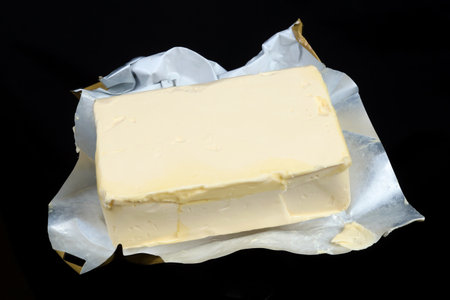 Creamy margarine in an industrial open foil packaging. Isolated on black  macro studio shotの写真素材