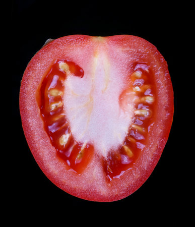 Half of a ripe red wintertomato . Isolated on black studio macro shotの写真素材
