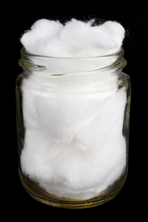 Glass jar with natural white cotton wool. Isolated on black night macroの写真素材