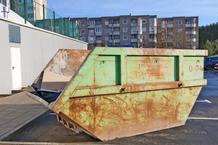 Green  rusty aged steel container for construction and industrial waste installed in a old  residential area of the European cityの写真素材