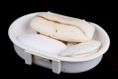Old rustic dry cracked white soaps slices  in plastic broken dishe. Isolated on black macro