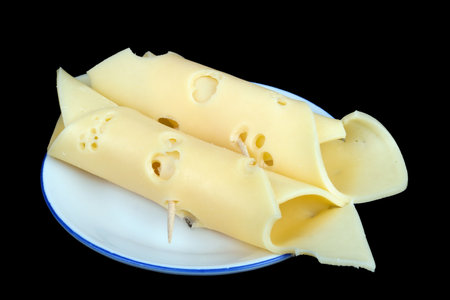 Two rolls of parmesan cheese lie on a white plate. Isolated on black studio macroの写真素材