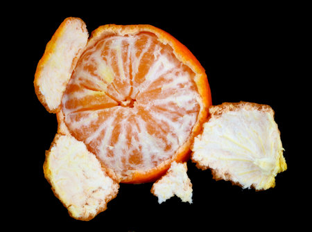 Start of cleaning ripe orange mandarin fruit. Isolated on black  studio macro shotの写真素材