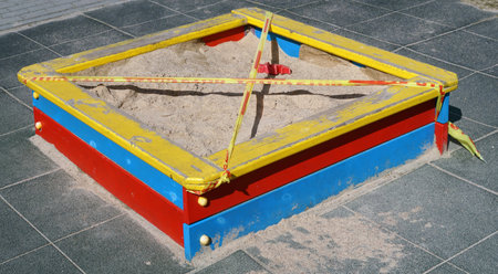 Wooden  sandbox  on childrens playground closed    with stop tape  during the epidemic