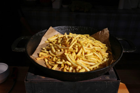 A pile of fried potatoes lies on a black  frying pan