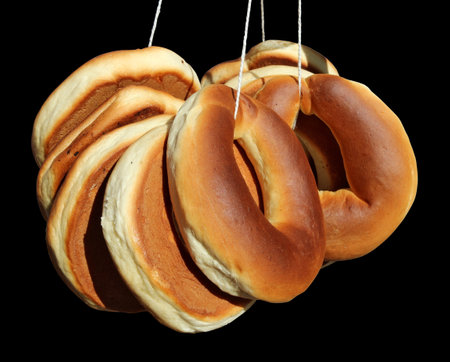 Traditional folk bagel donuts in the form of rings on a rope. Isolated on black