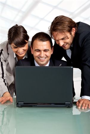 three happy businesspeople with a laptop, laughingの写真素材