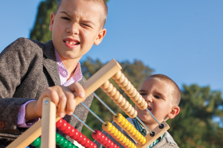 Back to school two confused little boys playing with wooden abacus in the park. One arround seven, the ather four.の写真素材