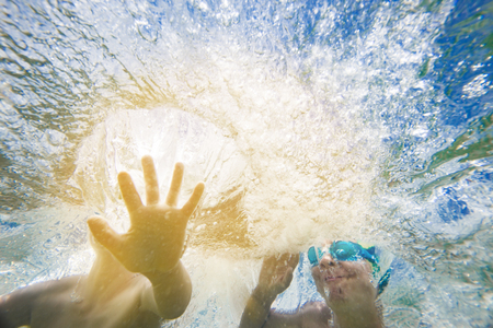 Underwater jumping kids with splashing hands and copy space over them.の写真素材