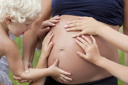 Childrens hands on a pregnant belly.の写真素材