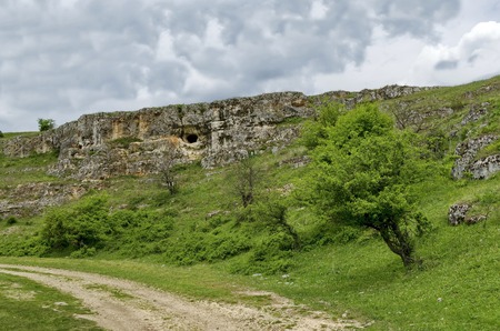 General view toward sedimentary rock with cave in the field, Ludogorie, Bulgariaの写真素材