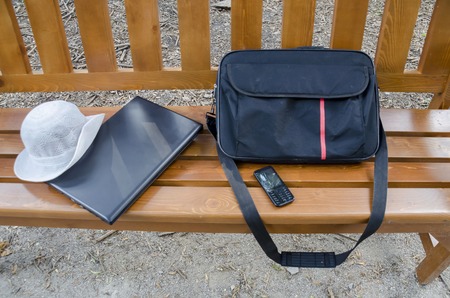 Shut a laptop computer, bag, phone  and hat on  wooden bench in the park, Sofia, Bulgariaの写真素材