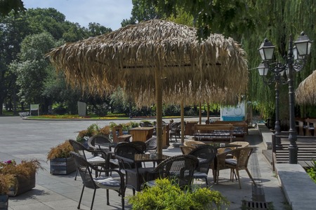 View of cosy nook for summer relaxation below palm sunshade with table, chair and wooden bench, park  Borisova gradina, Sofia, Bulgariaの写真素材