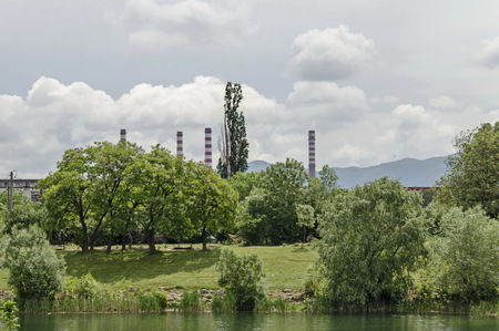 Spring panorama of a part of residential district and Thermoelectric power plant neighborhood along a lake with green trees, shrubs, flowers, Drujba, Sofia, Bulgariaの写真素材