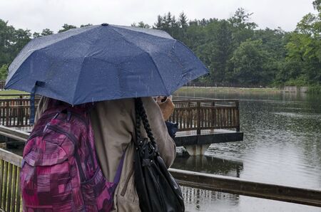 Rainy day walk with umbrellas in Rila Park near town Dupnitsa, Bulgaria