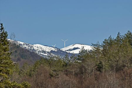 Wind turbine farm on a hillside in the background snowy Teteven balkan, Bulgaria