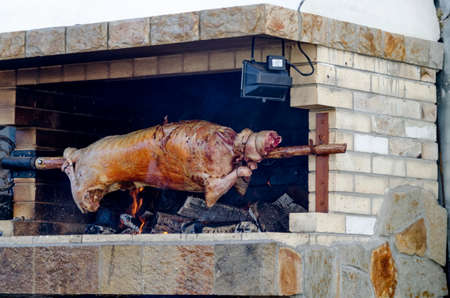 Lamb, roasted whole on a skewer over an open fire in an updated setting  in the resort of Borovets, Rila Mountain, Bulgariaの写真素材