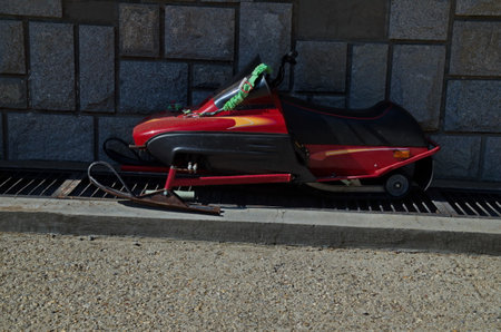 Red scooter, parked on the sidewalk next to a fence at the foot of a mountain in Bulgaria