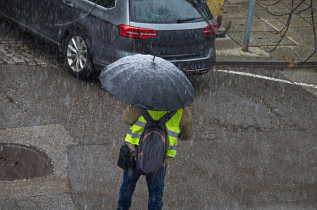 Moment of a storm with strong wind and heavy snowfall on a street with parked cars, as the walks...