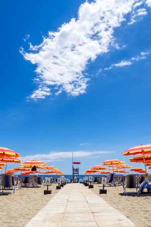 Entrance to a sandy beach with sun loungers and parasols in Italy, Europe.の写真素材
