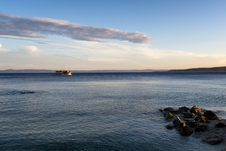 A small cruise ship on the Adriatic Sea in the evening near Baska Voda resort on the Makarska Riviera in Croatia, Europe.の写真素材