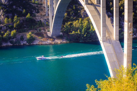 A white boat and scooter in the sea bay under bridge. The national park Krka in Croatia, Europe.の写真素材