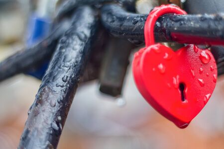 Heart-shaped love padlock with drops of rain in close-up view. の写真素材