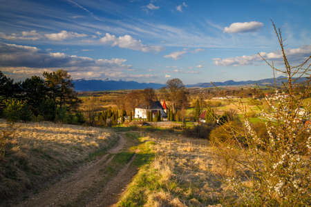 Sunny spring rural landscape, path leading to the church in the valley with mountains at the background. Turiec Valley in Slovakia, Europe.の写真素材