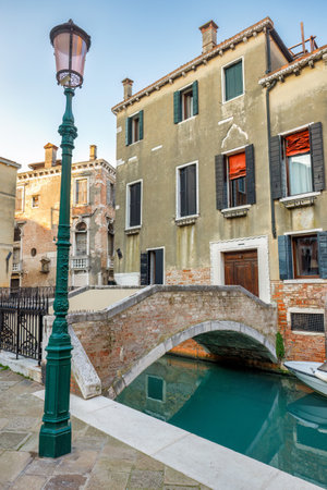 Canal with stone bridge and historic buildings in Venice, Italy, Europe.の写真素材