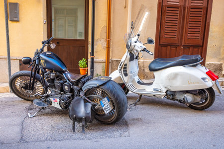 CASTELLAMMARE DEL GOLFO, ITALY - JULY 15, 2023: Harley Davidson and Vespa motorcycles on a street.のeditorial素材