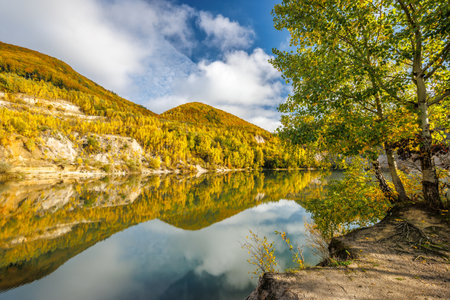 Autumn landscape with reflection of colorful hills in the lake. Flooded quarry near the village Sutovo in Slovakia, Europe.の写真素材