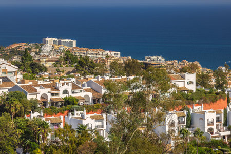 Coastal community homes overlooking the ocean. Whitewashed buildings and lush greenery against a deep blue sea.の写真素材