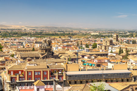 Granada town in Spain. Panoramic view of a historic city, showcasing terracotta rooftops, ancient architecture, and a sprawling landscape under a clear blue sky.の写真素材