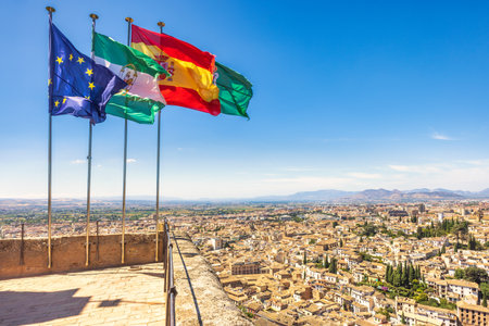 Granada town in Spain from the Alhambra complex. Panoramic city view with flags waving under a clear...
