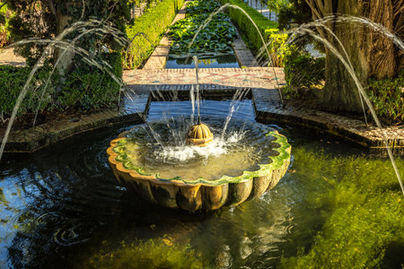The Generalife Palace at the Alhambra complex in Granada town, Andalusia, Spain. Serene garden fountain with cascading water and lush greenery. Tranquil outdoor scene.の写真素材