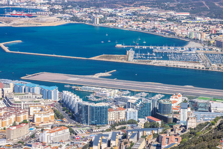 Gibraltar, United Kingdom - September 10, 2024: Aerial view of a coastal city with a runway, marina, and harbor.のeditorial素材