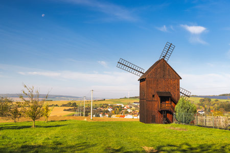 Velke Tesany, Czech Republic - October 21, 2024: Vintage wooden windmill on a grassy hill against a...