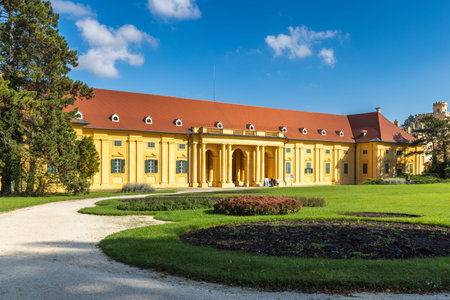 Lednice, Czech Republic - October 12, 2024: The Lednice castle. View of a yellow building with a red roof, classical facade, pillars, and windows with green frames surrounded by a green lawn.のeditorial素材