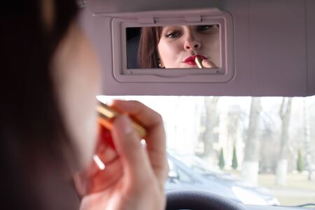 the Girl paints lips in carの写真素材