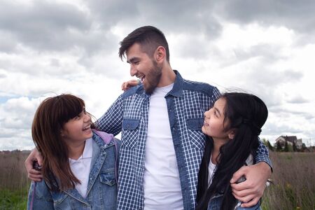 the Happy father hugs two daughtersの写真素材