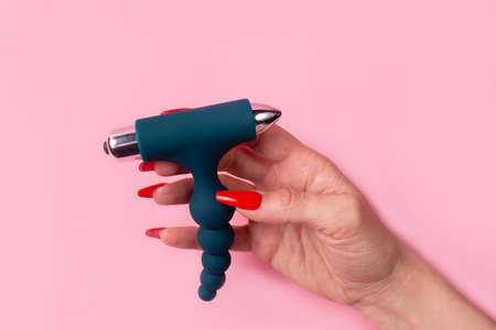 the Dildo in hand on a pink background, sex toy
