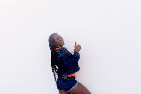 the Happy African American dances against white wall