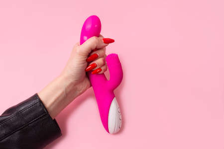 the Dildo in hand on a pink background, sex toy