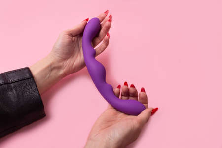 the Dildo in hand on a pink background, sex toyの写真素材