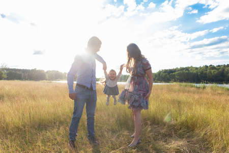 the Happy parents rock the child in their arms, in natureの写真素材
