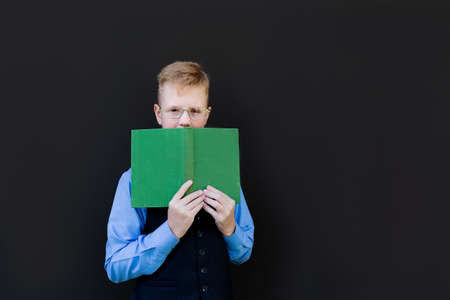 the schoolboy with a book on a black backgroundの写真素材